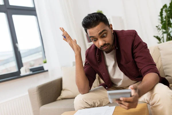 Confundido hombre con papeles y calculadora en casa — Foto de Stock