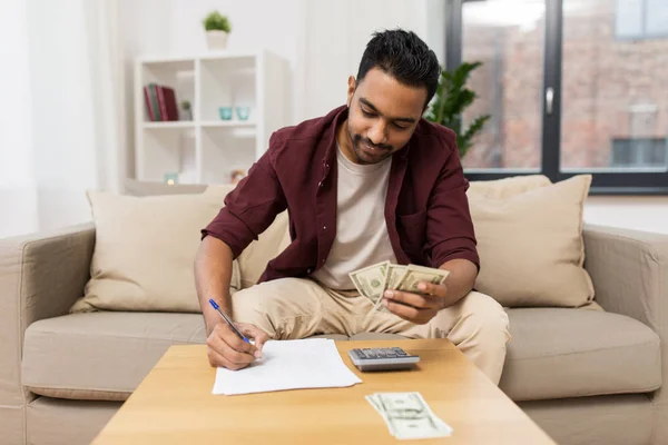 Man with money and calculator filling papers — Stock Photo, Image