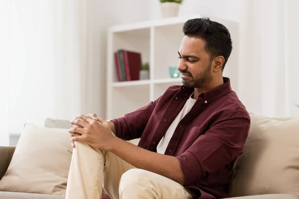 Unhappy man suffering from pain in leg at home — Stock Photo, Image