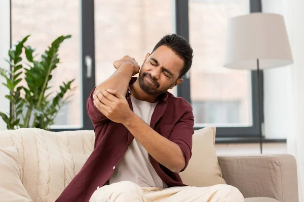 Unhappy man suffering from pain in hand at home — Stock Photo, Image