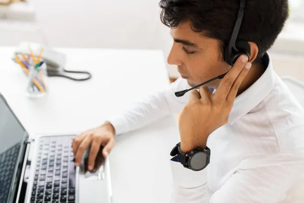 Hombre de negocios con auriculares y portátil en la oficina —  Fotos de Stock