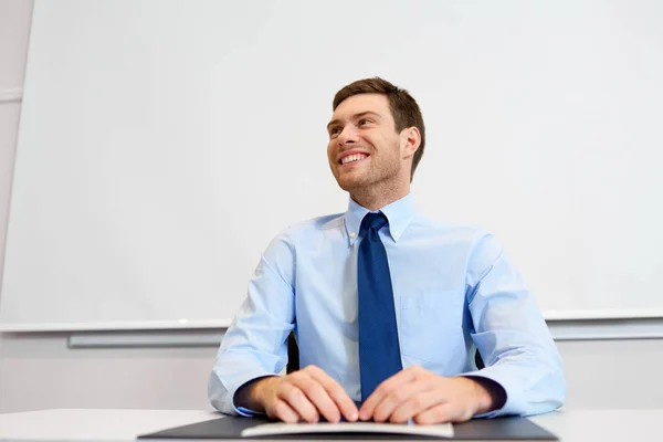 Lachende jonge zakenman zitten op kantoor tafel — Stockfoto