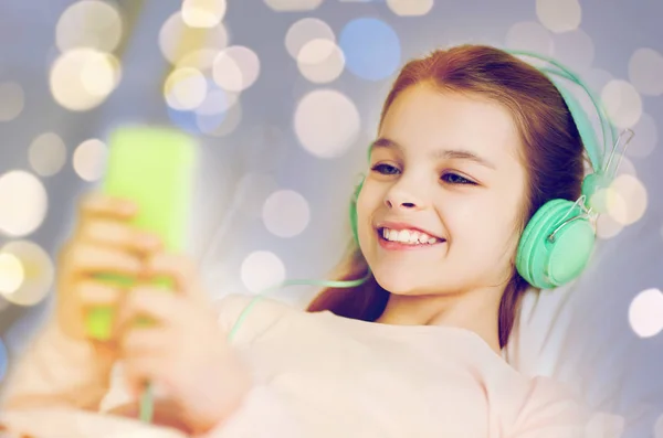 Mädchen mit Kopfhörer und Smartphone über Licht — Stockfoto