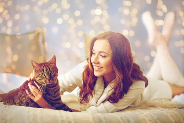 Happy young woman with cat lying in bed at home — Stock Photo, Image