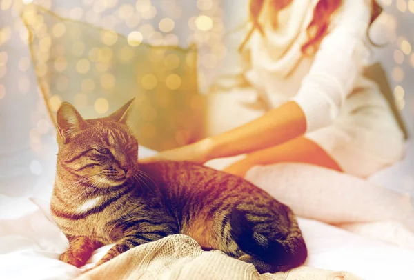 Νεαρή γυναίκα με γάτα ξαπλωμένη στο κρεβάτι στο σπίτι — Φωτογραφία Αρχείου