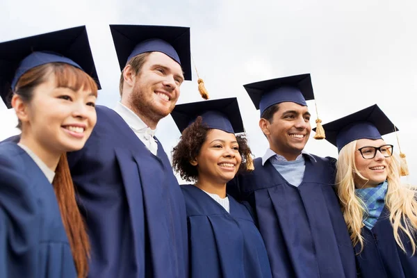 Happy students or bachelors in mortar boards — Stock Photo, Image