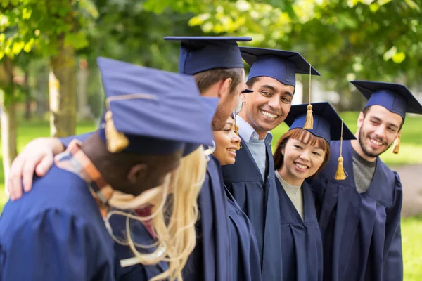 Happy students or bachelors in mortar boards — Stock Photo, Image