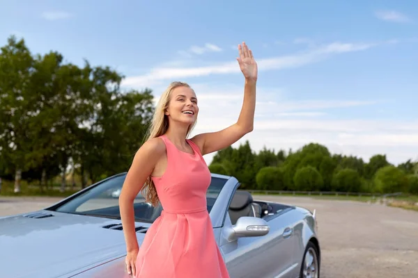 Feliz joven mujer en coche convertible agitando la mano —  Fotos de Stock