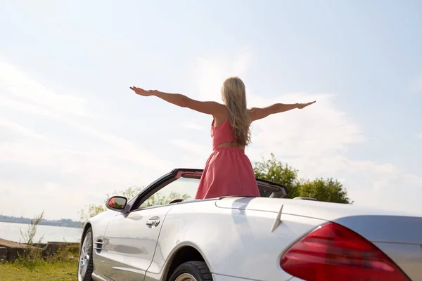 Ευτυχισμένος νεαρή γυναίκα σε μετατρέψιμο αυτοκίνητο με φοντο τη θαλασσα — Φωτογραφία Αρχείου