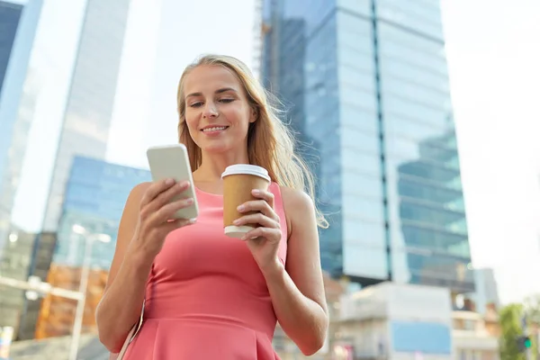 Женщина с кофе и смартфоном в городе — стоковое фото