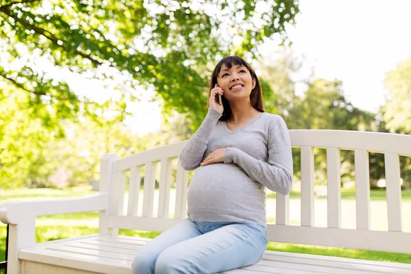 Zwangere Aziatische vrouw belt op smartphone bij park — Stockfoto