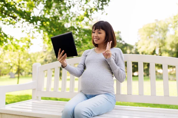 Glücklich schwangere Asiatin mit Tablet-PC im Park — Stockfoto
