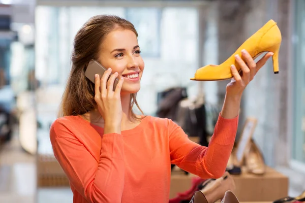 Jonge vrouw belt op smartphone bij schoenenwinkel — Stockfoto