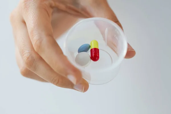 Close-up da mão feminina com pílulas no copo de medicina — Fotografia de Stock