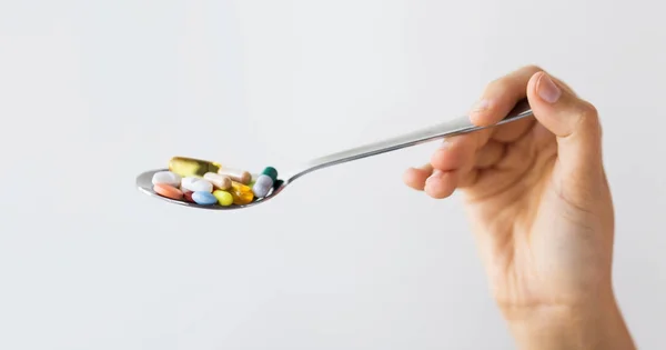 Close up of female hand holding spoon with pills — Stock Photo, Image