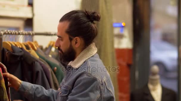 Hombre eligiendo ropa en tienda de ropa vintage — Vídeo de stock