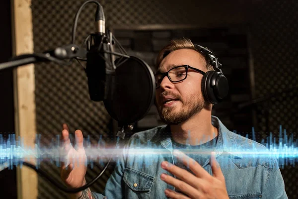 Homem com fones de ouvido cantando no estúdio de gravação — Fotografia de Stock