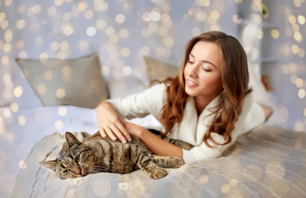 Feliz joven con gato acostado en la cama en casa —  Fotos de Stock