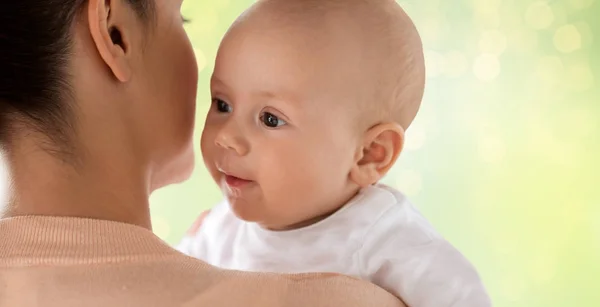 Close up van happy baby met moeder over groen — Stockfoto