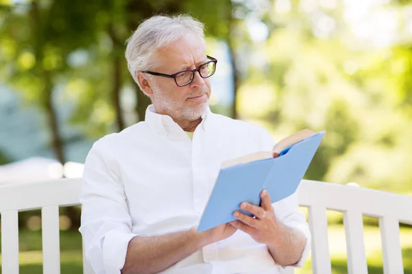 Senior man leesboek in zomer park — Stockfoto