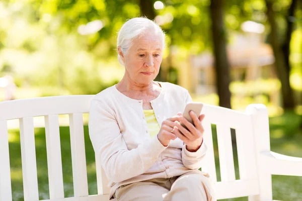 Donna anziana con smartphone al parco estivo — Foto Stock