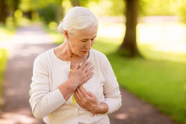 Senior vrouw gevoel ziek in zomer park — Stockfoto