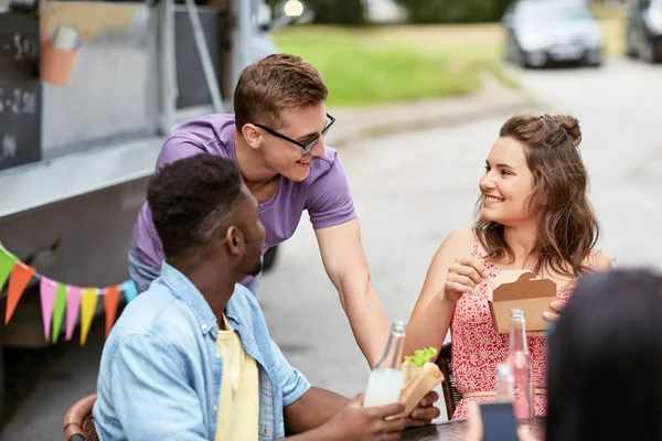 Amis heureux avec des boissons manger au camion de nourriture — Photo