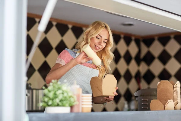 Feliz vendedora fazendo wok no caminhão de alimentos — Fotografia de Stock