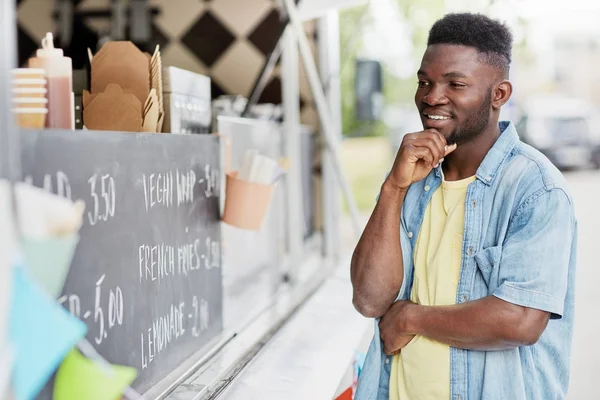 Client masculin regardant le panneau d'affichage au camion de nourriture — Photo