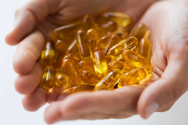 Hands holding cod liver oil capsules — Stock Photo, Image