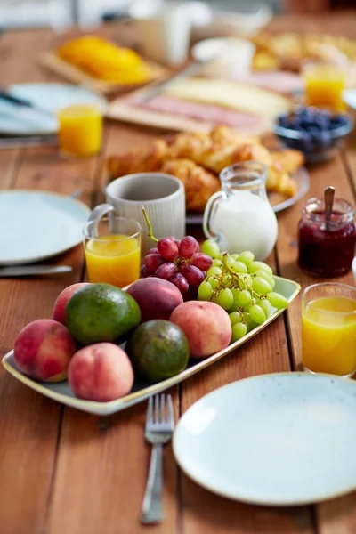 Fruits, jus et autres aliments sur la table au petit déjeuner — Photo