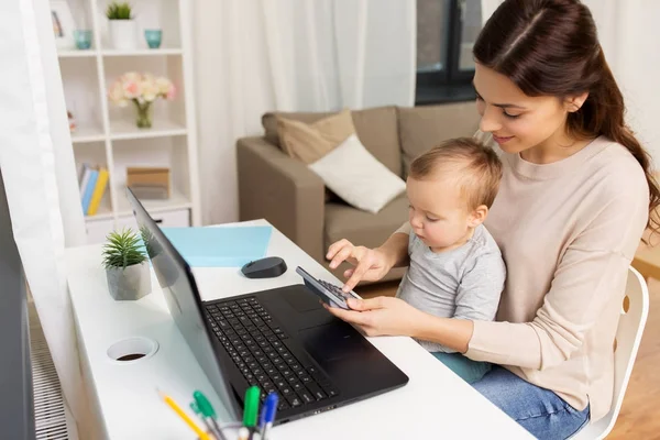 Madre felice con bambino e laptop che lavorano a casa — Foto Stock