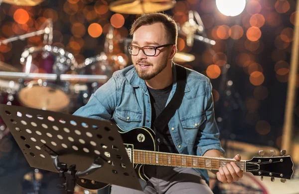 Músico tocando la guitarra en el estudio sobre luces — Foto de Stock