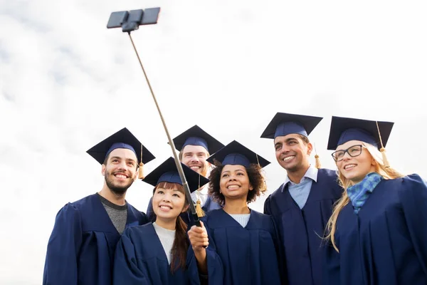 Grupo de estudantes felizes ou graduados que tomam selfie — Fotografia de Stock