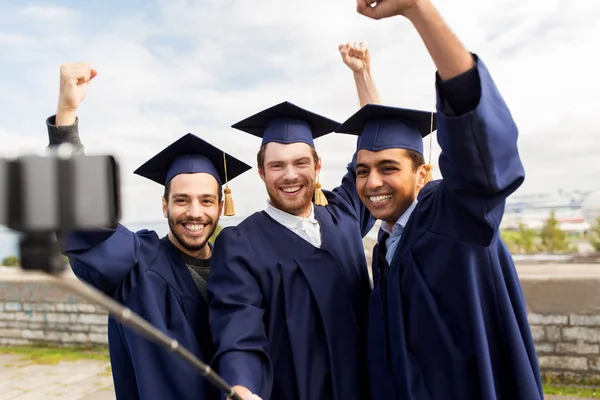 Estudantes do sexo masculino felizes ou graduados que tomam selfie — Fotografia de Stock