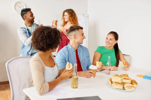 Happy friends or team eating at office — Stock Photo, Image