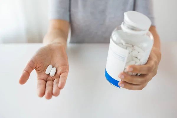 Primer plano de las manos sosteniendo píldoras medicinales y frasco — Foto de Stock