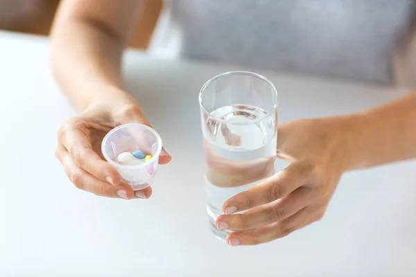 Primer plano de las manos con pastillas y vaso de agua — Foto de Stock