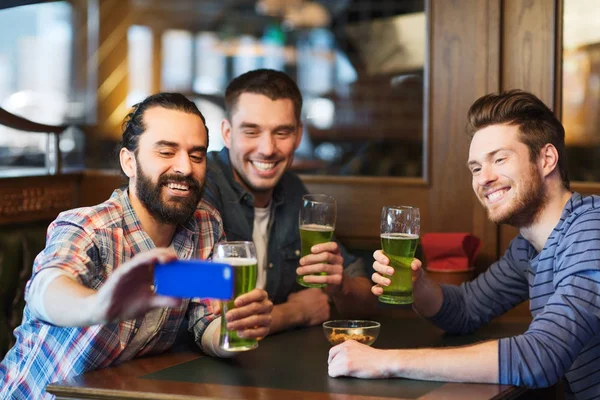 Amigos tomando selfie con cerveza verde en el pub —  Fotos de Stock