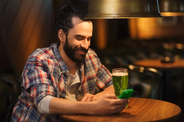 Man med smartphone och grön öl textning på bar — Stockfoto