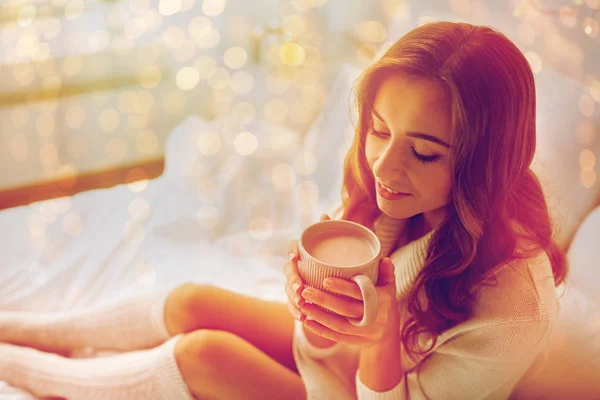 Mujer feliz con taza de cacao en la cama en casa —  Fotos de Stock