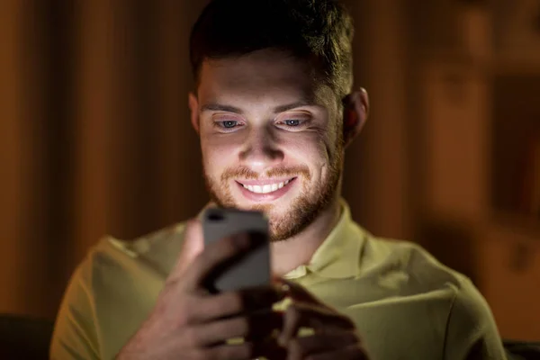 Χαρούμενος νεαρός άνδρας με το smartphone, το βράδυ — Φωτογραφία Αρχείου