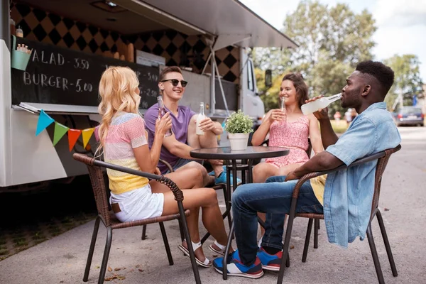 Amici con bevande seduti a tavola al food truck — Foto Stock