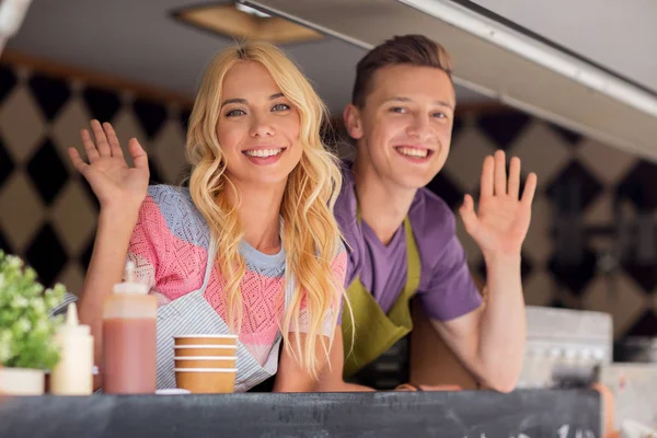 Szczęśliwy młodych sprzedawców machanie rękami w food truck — Zdjęcie stockowe