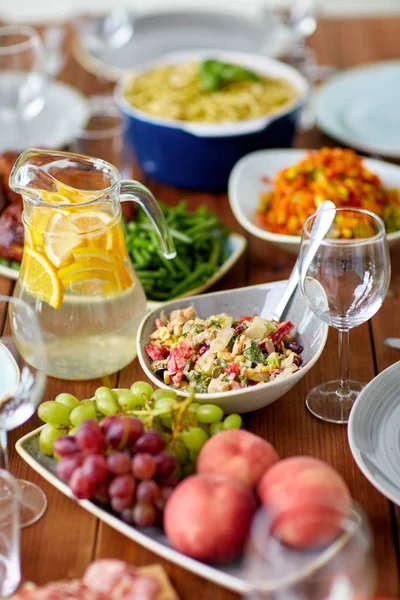 サラダ、水の水差し、木製のテーブルにその他の食品 — ストック写真