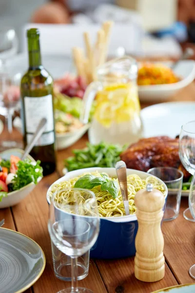 Těstoviny s bazalkou v misce a další jídlo na stole — Stock fotografie