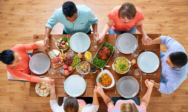 Group of people at table praying before meal — Stock Photo, Image