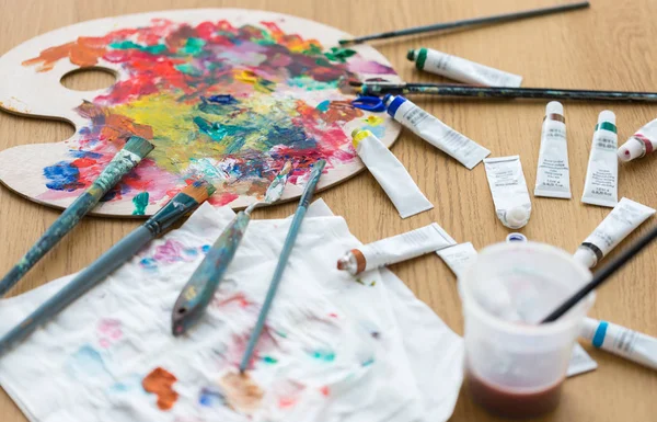 Palette, brushes and paint tubes on table — Stock Photo, Image