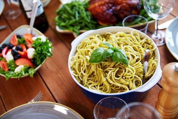 Pasta con basilico in ciotola e altri alimenti in tavola — Foto Stock