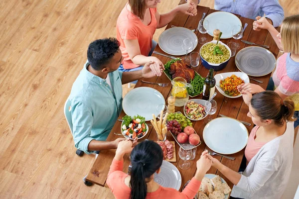 Group of people at table praying before meal — Stock Photo, Image